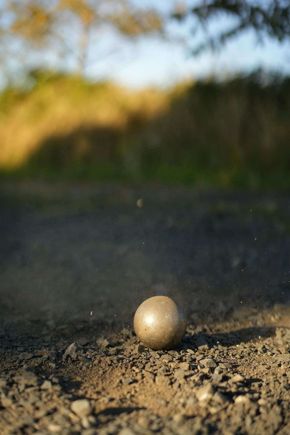 A pétanque boule landing in a puff of dust
